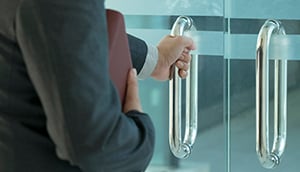 Businessman entering an office by opening out a glass door