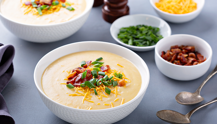 baked potato soup in a bowl with green onions, bacon, and cheese
